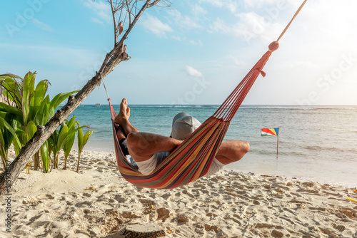 Tourist relaxing in a hammock on a tropical beach overlooking the Indian Ocean. La Digue island, Seychelles