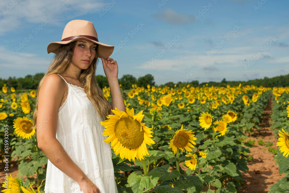 A Lovely Blonde Model Poses Outdoor While Enjoying The Summer Weather In A Field Of Wild Sunflowers