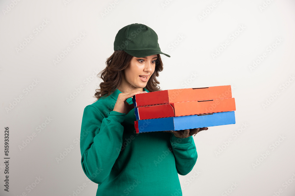 Delivery woman looking at pizza boxes with surprised expression Delivery woman looking at pizza boxes with surprised expression