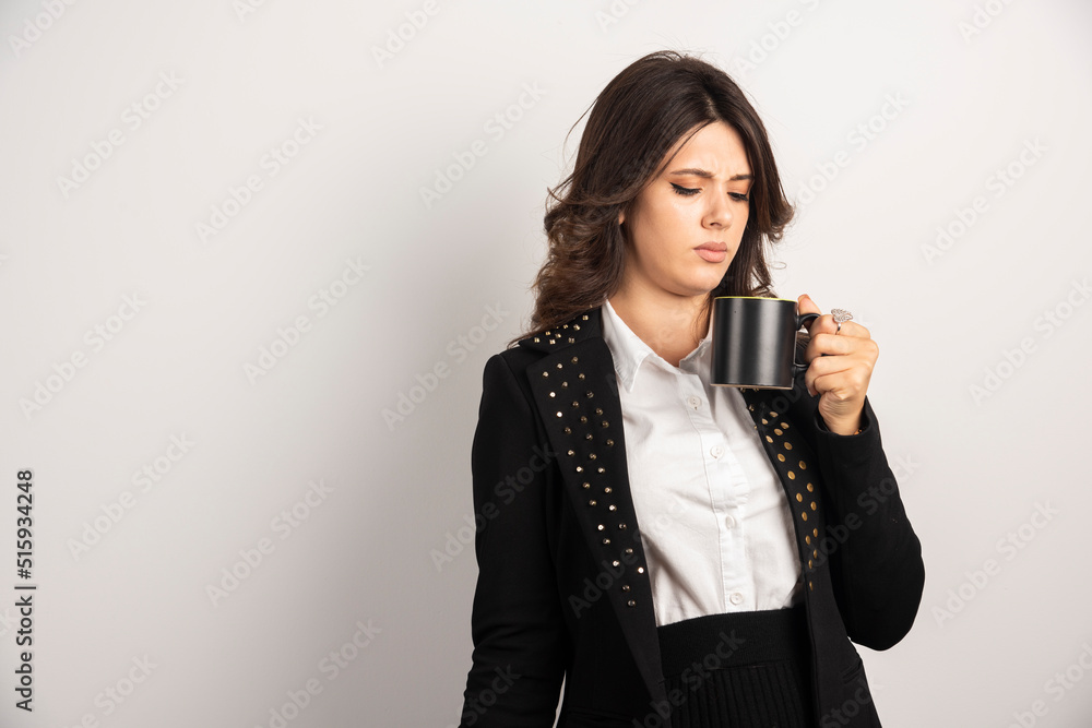 Female worker looking at cup with unreadable expression Female worker looking at cup with unreadable expression