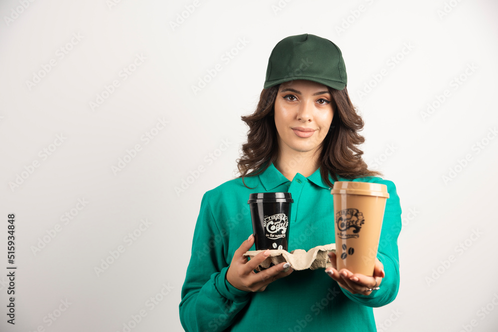 Female courier in green uniform holding coffee cups Female courier in green uniform holding coffee cups