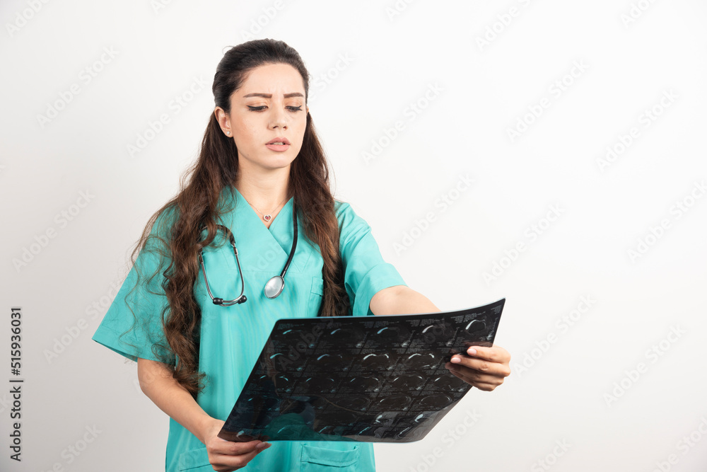 Young woman doctor looking on x-ray over white background