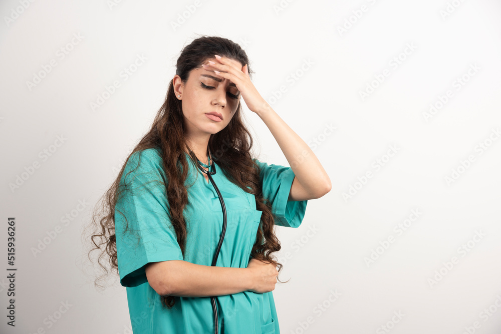 Portrait of female healthcare worker touching her head on white background Portrait of female healthcare worker touching her head on white background