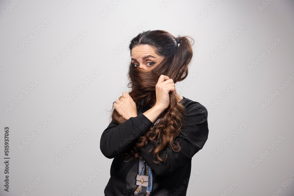 Adorable young girl covering face with hair on gray background Adorable young girl covering face with hair on gray background