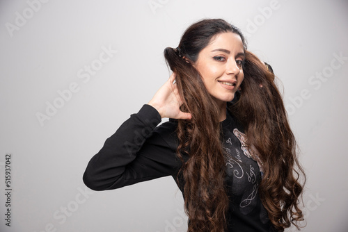 Young woman in casual sweatshirt showing her hair on gray background