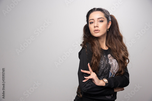 Young girl in printed sweatshirt standing on gray background