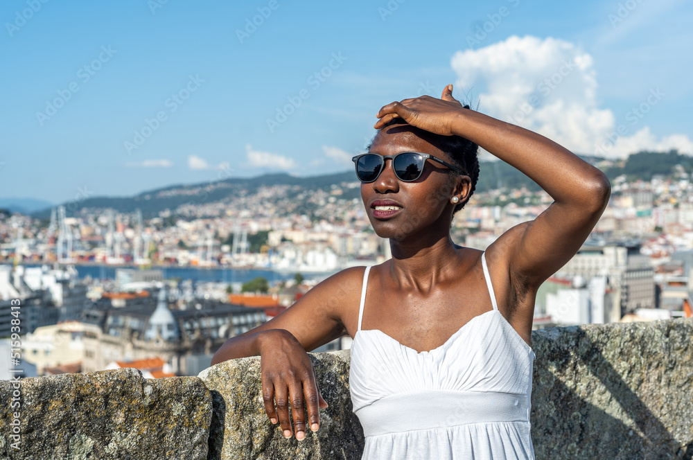 Woman wearing sunglasses on a hot day. Blurred city view background.
