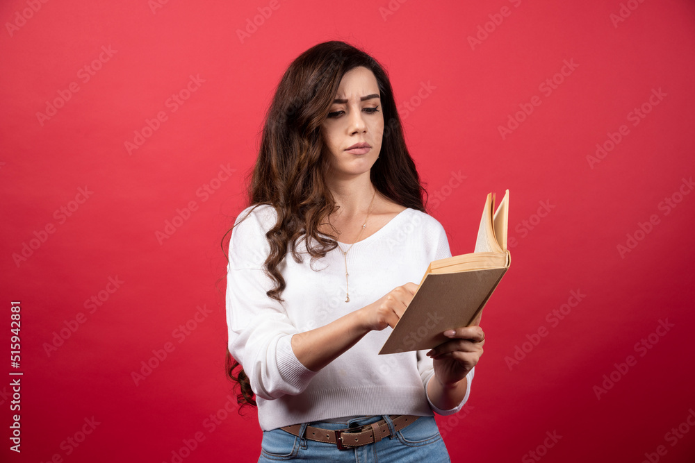 Young woman reading an interesting book on a red background Young woman reading an interesting book on a red background