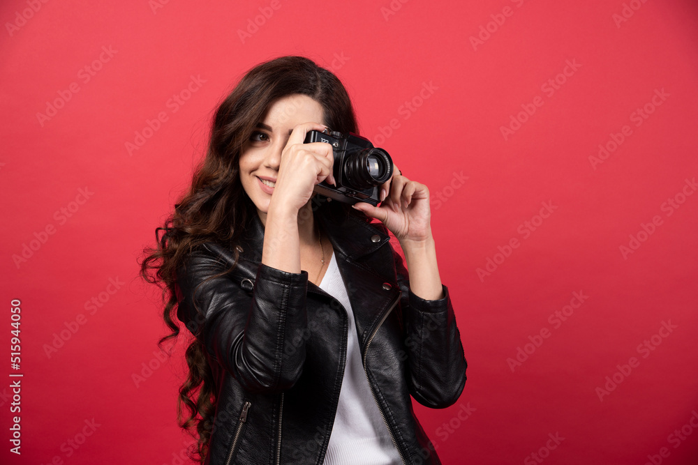 Woman photographer taking pictures with a photo camera on a red background Woman photographer taking pictures with a photo camera on a red background