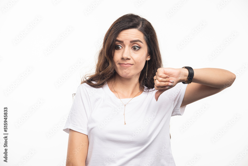 Wavy haired woman in white shirt giving thumbs down Wavy haired woman in white shirt giving thumbs down