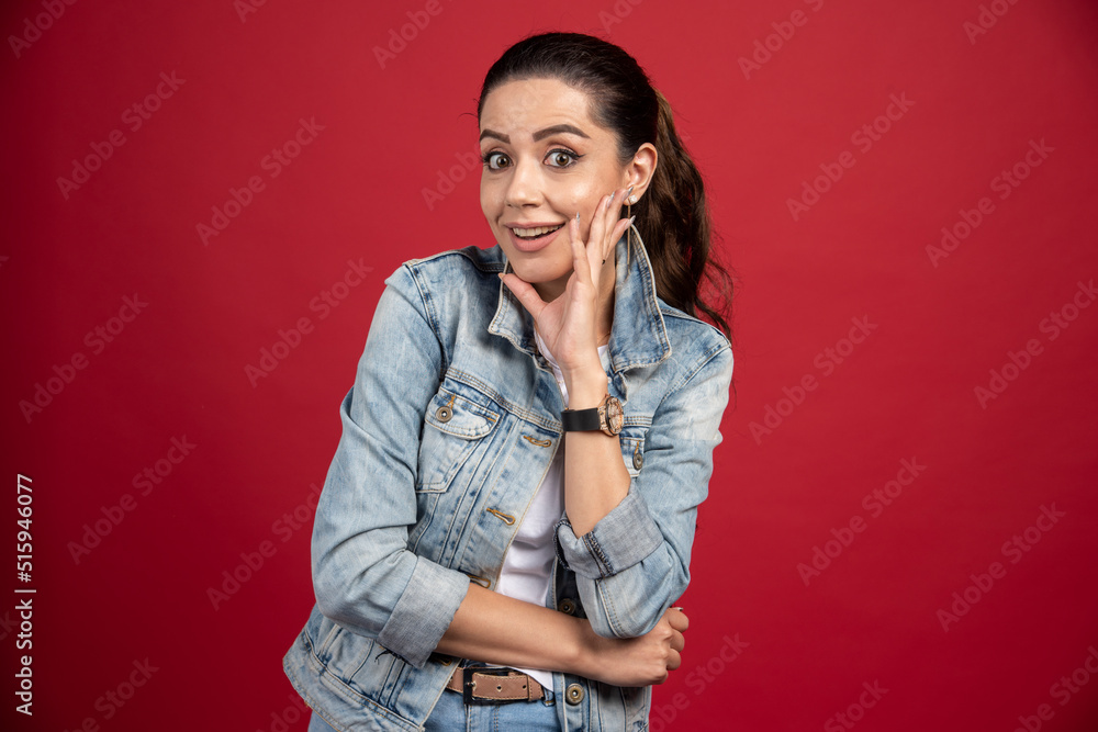 Beautiful woman in denim outfit standing on red background Beautiful woman in denim outfit standing on red background