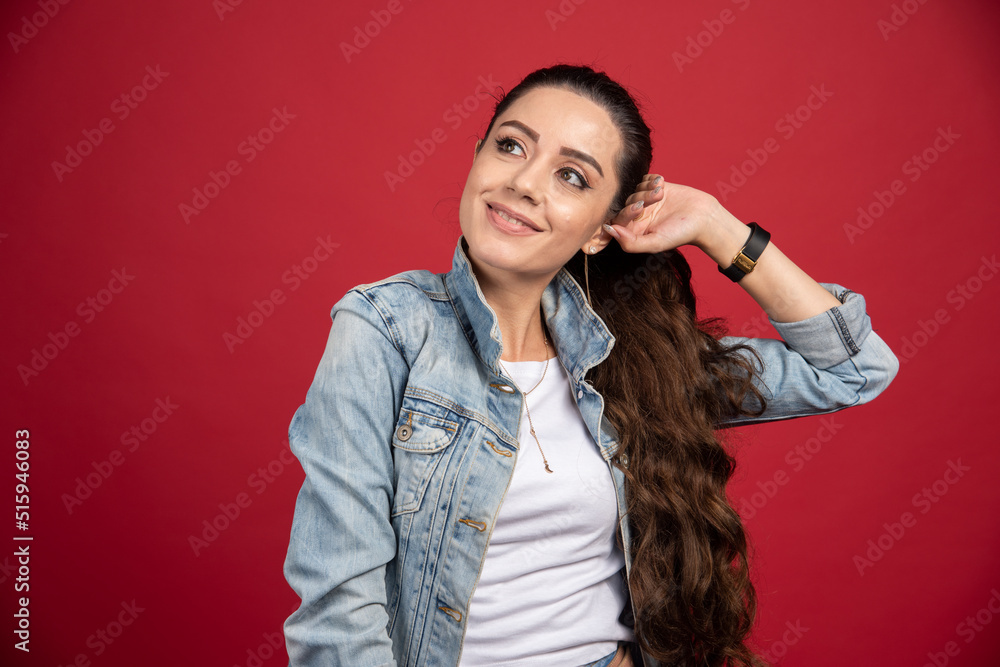 Beautiful woman in denim outfit posing on red background Beautiful woman in denim outfit posing on red background