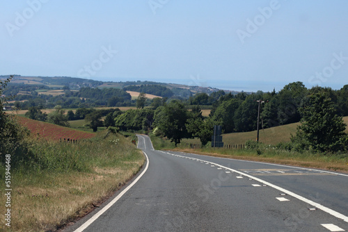 Downhill on an empty road in Somerset, England. Lush green rolling hills can be seen in the background