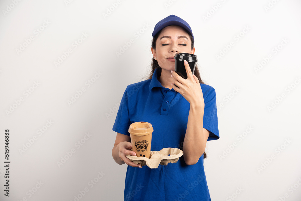 Young deliverywoman sniffs one cup of coffee Young deliverywoman sniffs one cup of coffee