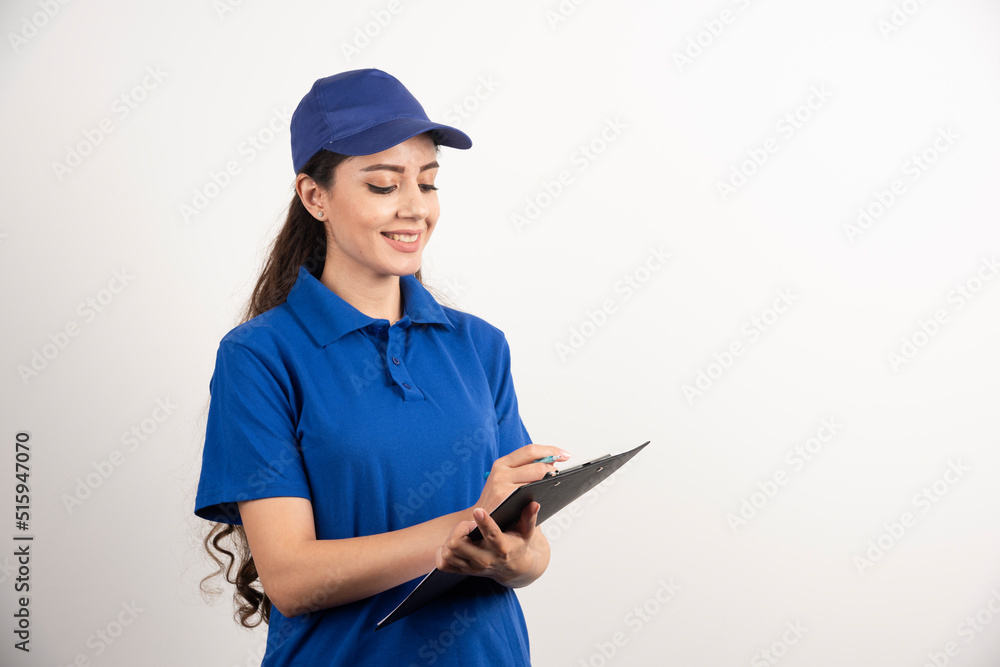 Young female courier in blue scrubs holding a clipboard