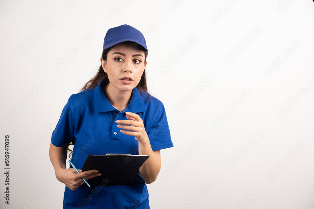 Young female courier in blue scrubs holding a clipboard