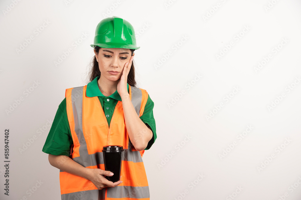 Young female constructor holding black cup Young female constructor holding black cup