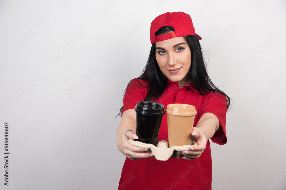 Happy young woman offering two cups of coffee on white background Happy young woman offering two cups of coffee on white background