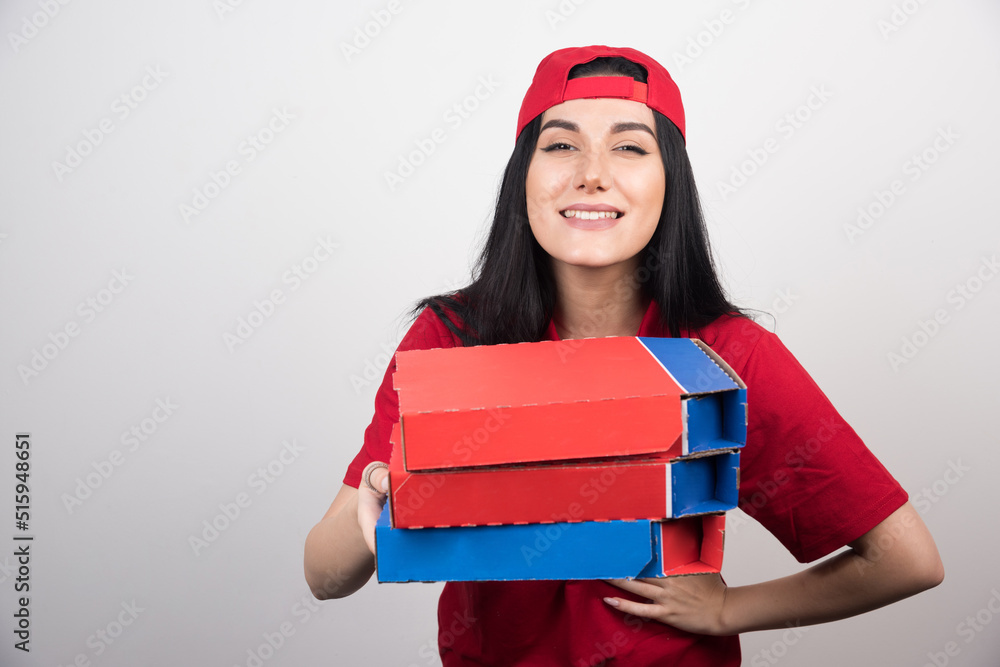 Young delivery woman with cap holding a three boxes of pizza on white background Young delivery woman with cap holding a three boxes of pizza on white background