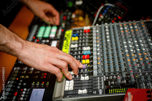 Hand of a sound engineer on sound console mixer. Equalizer control © 9parusnikov