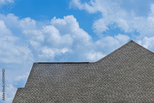 Construction roof of a house is being covered with asphalt shingles while building