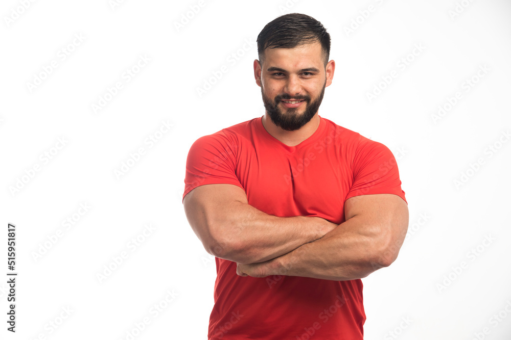Sportive man in red showing his muscles Sportive man in red showing his muscles