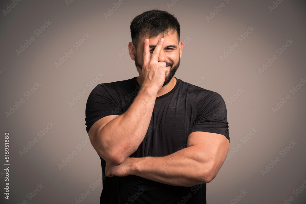 Sportive man in black shirt makes peace sign