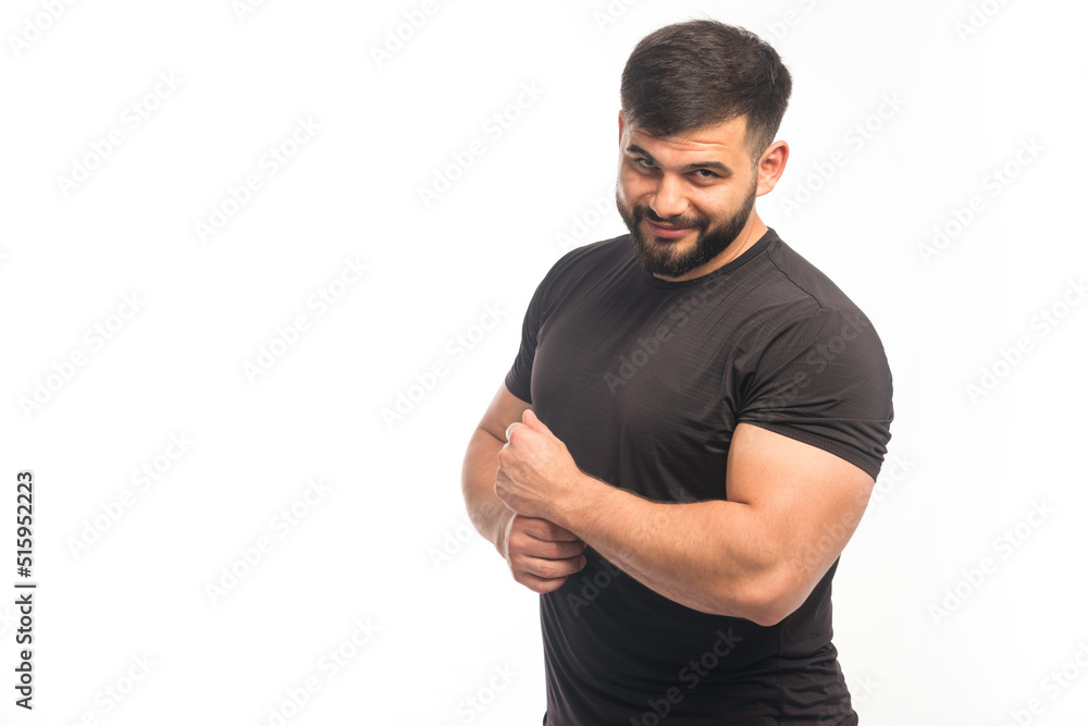 Fototapeta premium Sportive man in black shirt demonstrating his arm muscles