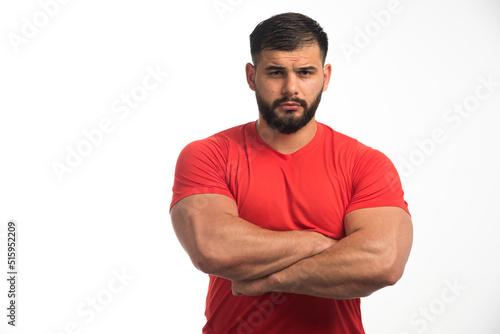 Sportive man in red shirt demonstrating his upper muscles