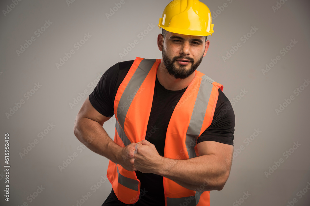 Engineer in orange uniform and yellow helmet with big muscles Engineer in orange uniform and yellow helmet with big muscles