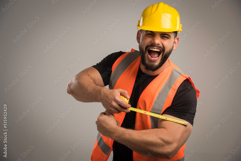 Engineer in orange uniform and yellow helmet using ruler Engineer in orange uniform and yellow helmet using ruler