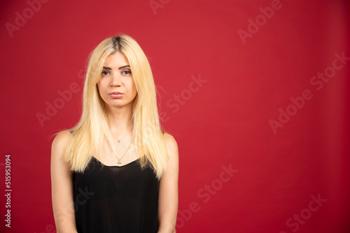 Portrait of blonde woman standing on red background