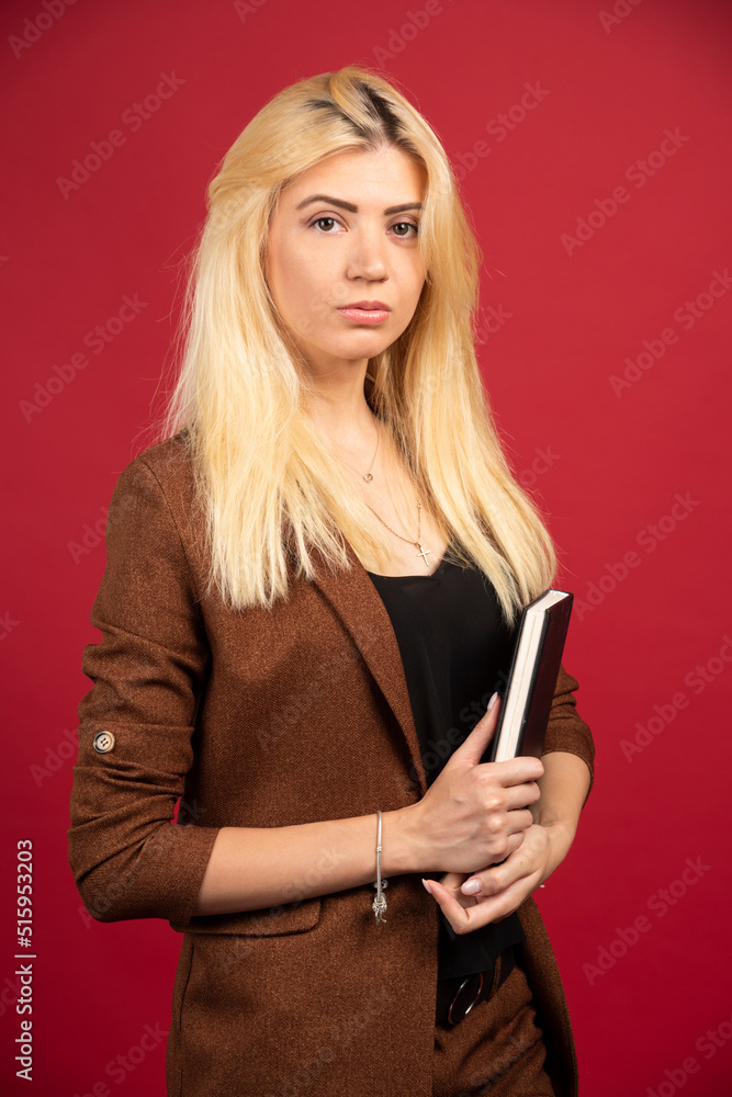 Young employee with notebook standing on red background Young employee with notebook standing on red background