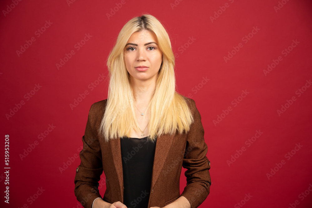 Fototapeta premium Office employee in brown jacket posing on red background