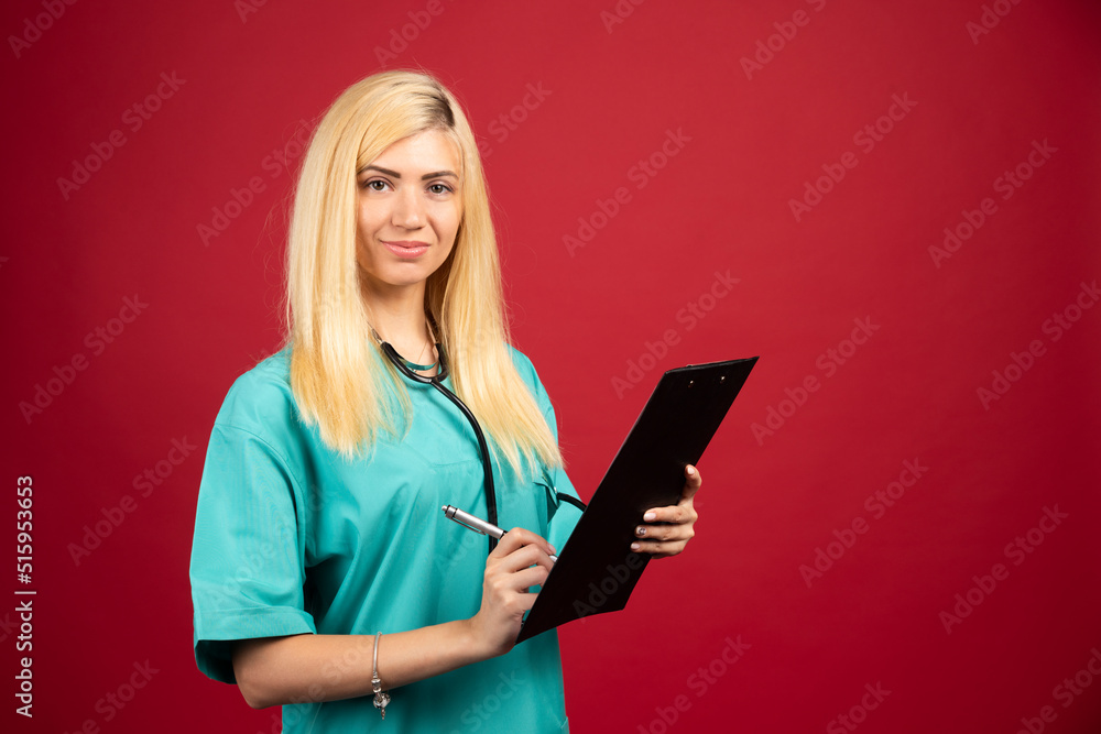 Young doctor in uniform writing on clipboard