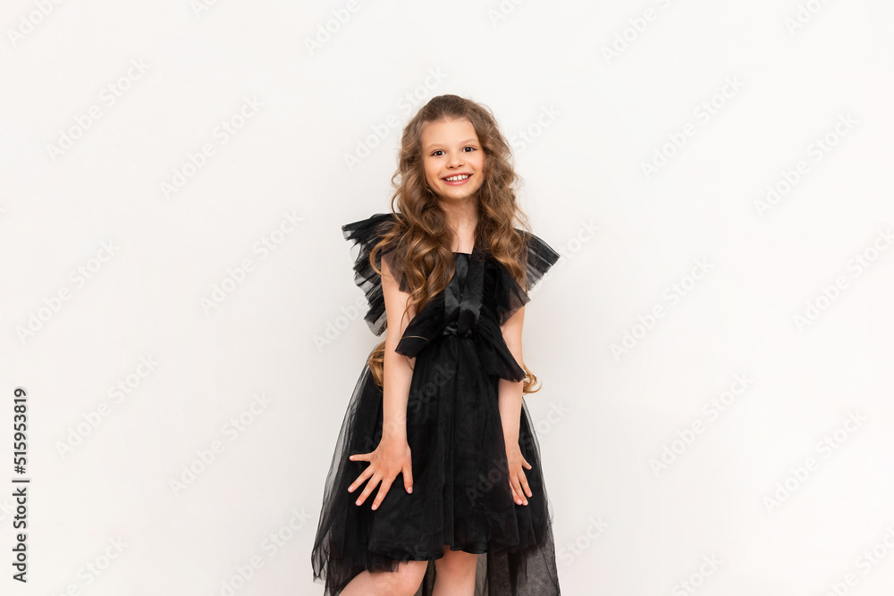 A charming little girl with curly hair and a fluffy dress on a white isolated background. A beautiful princess on Black Friday. A charming little girl with curly hair and a fluffy dress on a white isolated background. A beautiful princess on Black Friday.