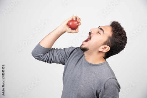 Brunette man trying to eat red apple