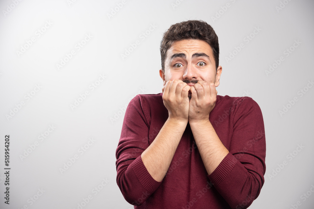An afraid brunette man over a gray wall An afraid brunette man over a gray wall