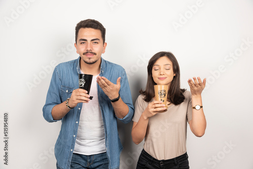 Young man and woman sniffs aroma coffee from cups