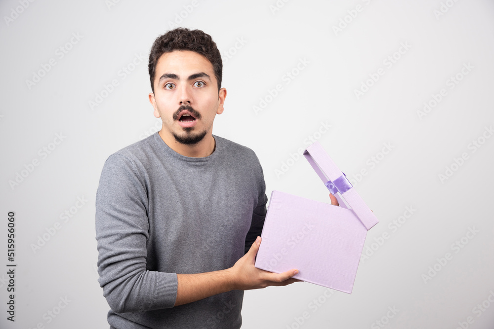 Shocking man with an opened purple box over a white wall Shocking man with an opened purple box over a white wall