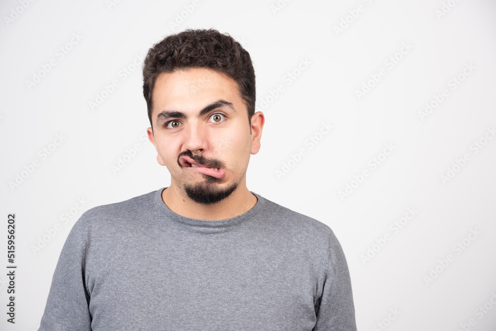 Fototapeta premium A young man doing a funny face over a white wall