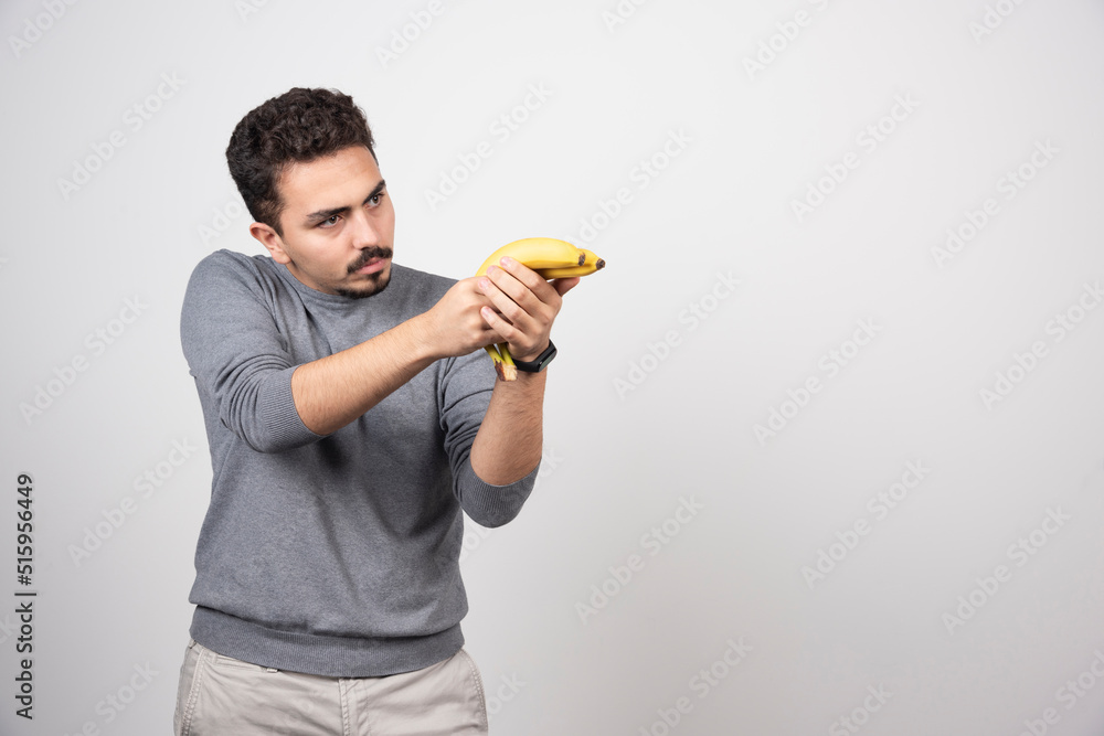 A young man holding two fresh bananas A young man holding two fresh bananas