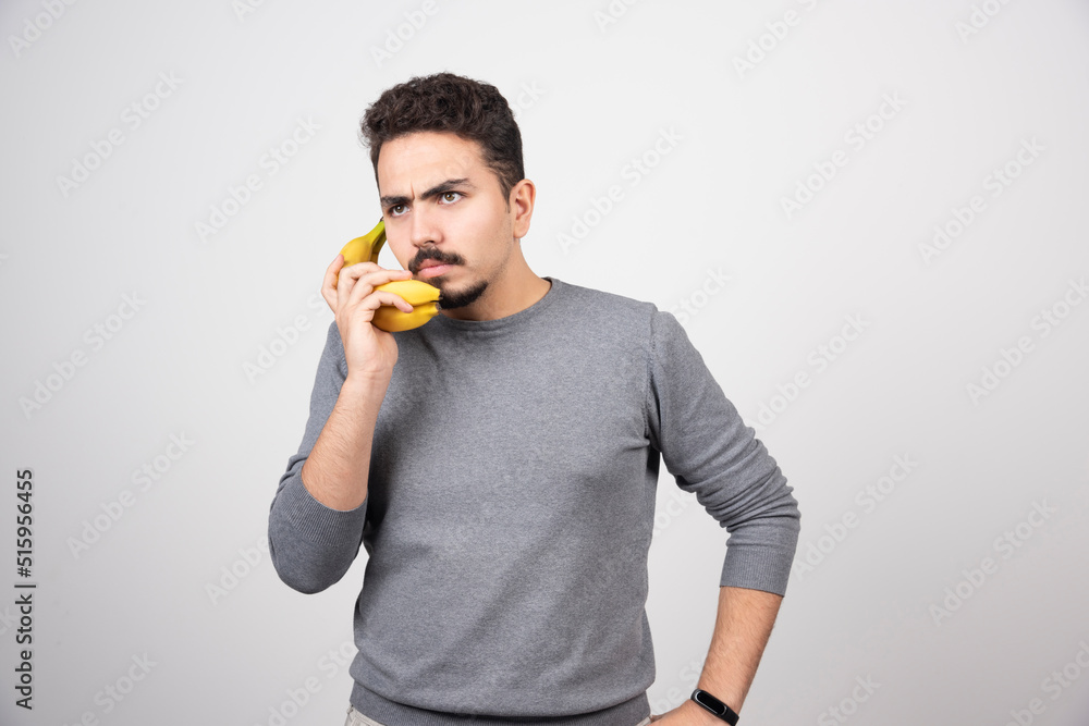 A young man model holding a banana as a phone A young man model holding a banana as a phone