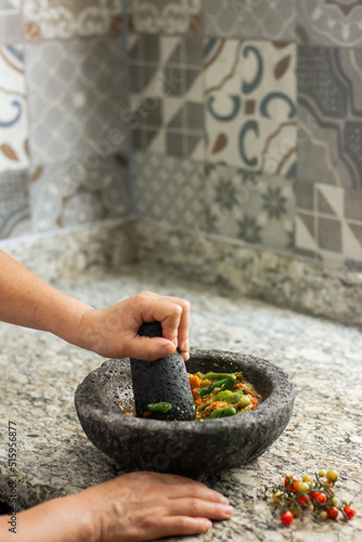 Hispanic person making mexican sauce in a molcajete