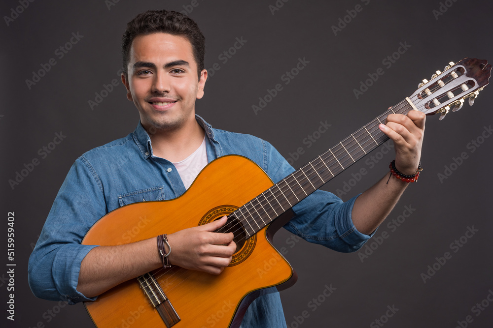 Smiling man playing guitar on dark background