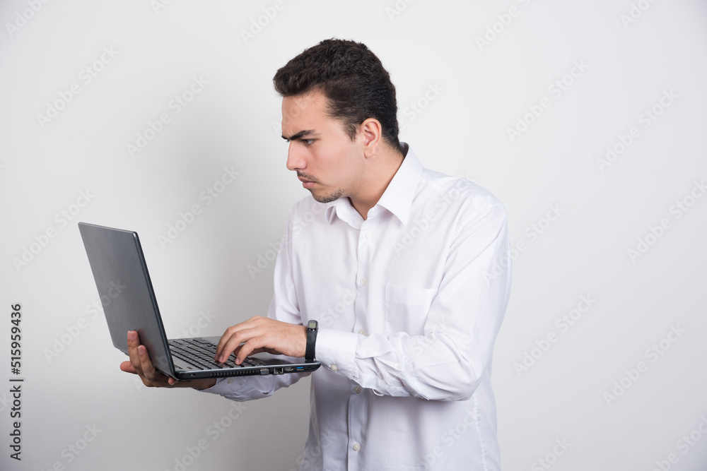 Businessman intensely looking at laptop on white background Businessman intensely looking at laptop on white background