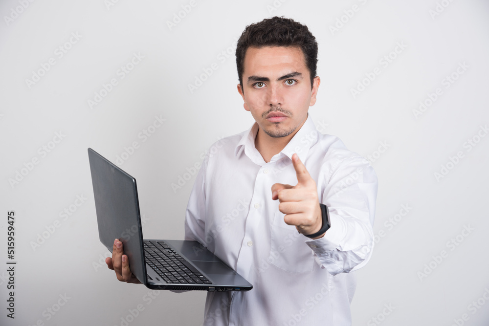 Businessman with laptop pointing at camera on white background Businessman with laptop pointing at camera on white background