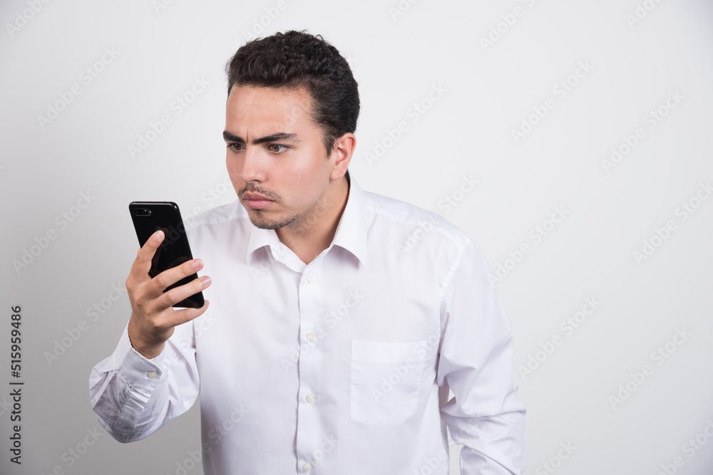Businessman looking intensely at telephone on white background
