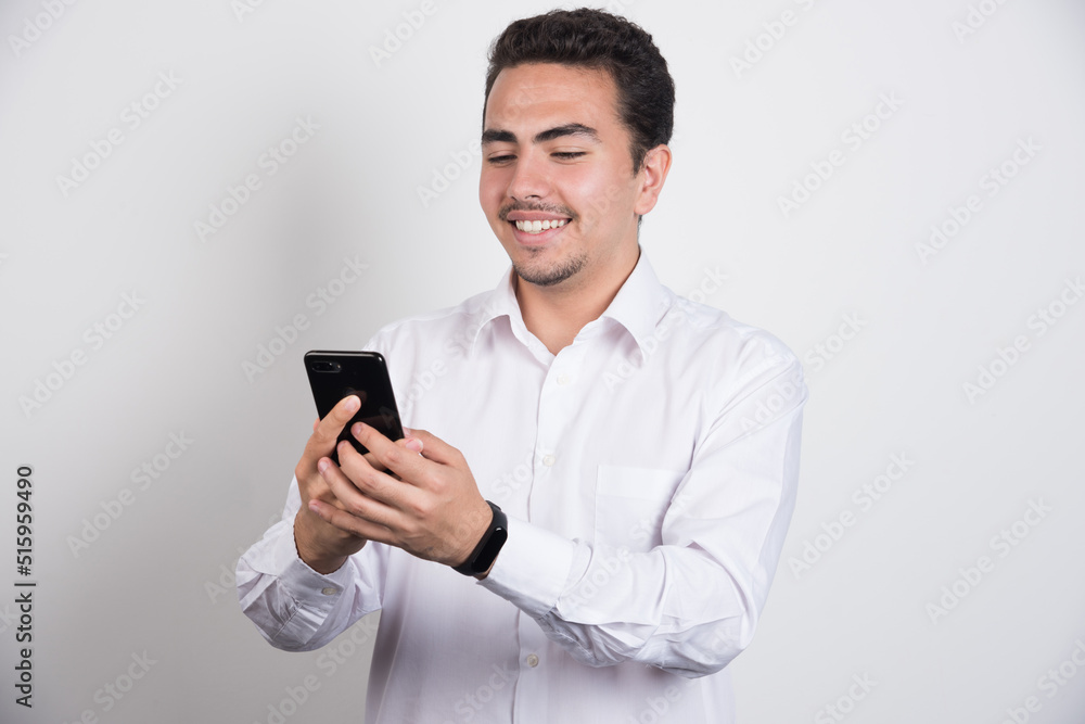 Smiling businessman looking at telephone on white background Smiling businessman looking at telephone on white background