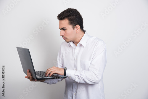 Businessman intensely looking at laptop on white background